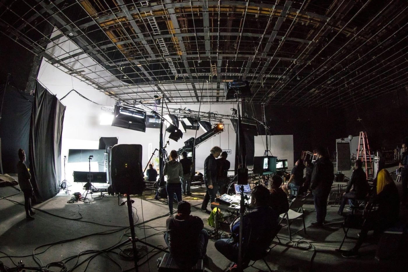 A lit soundstage with crew, rigging, and monitors